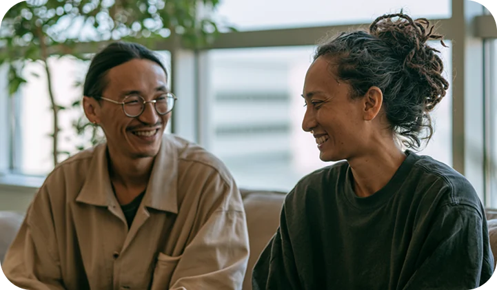 Two colleagues laughing together in a bright office