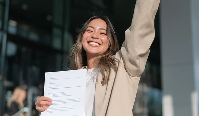 Team member celebrating with a document in hand outside an office building
