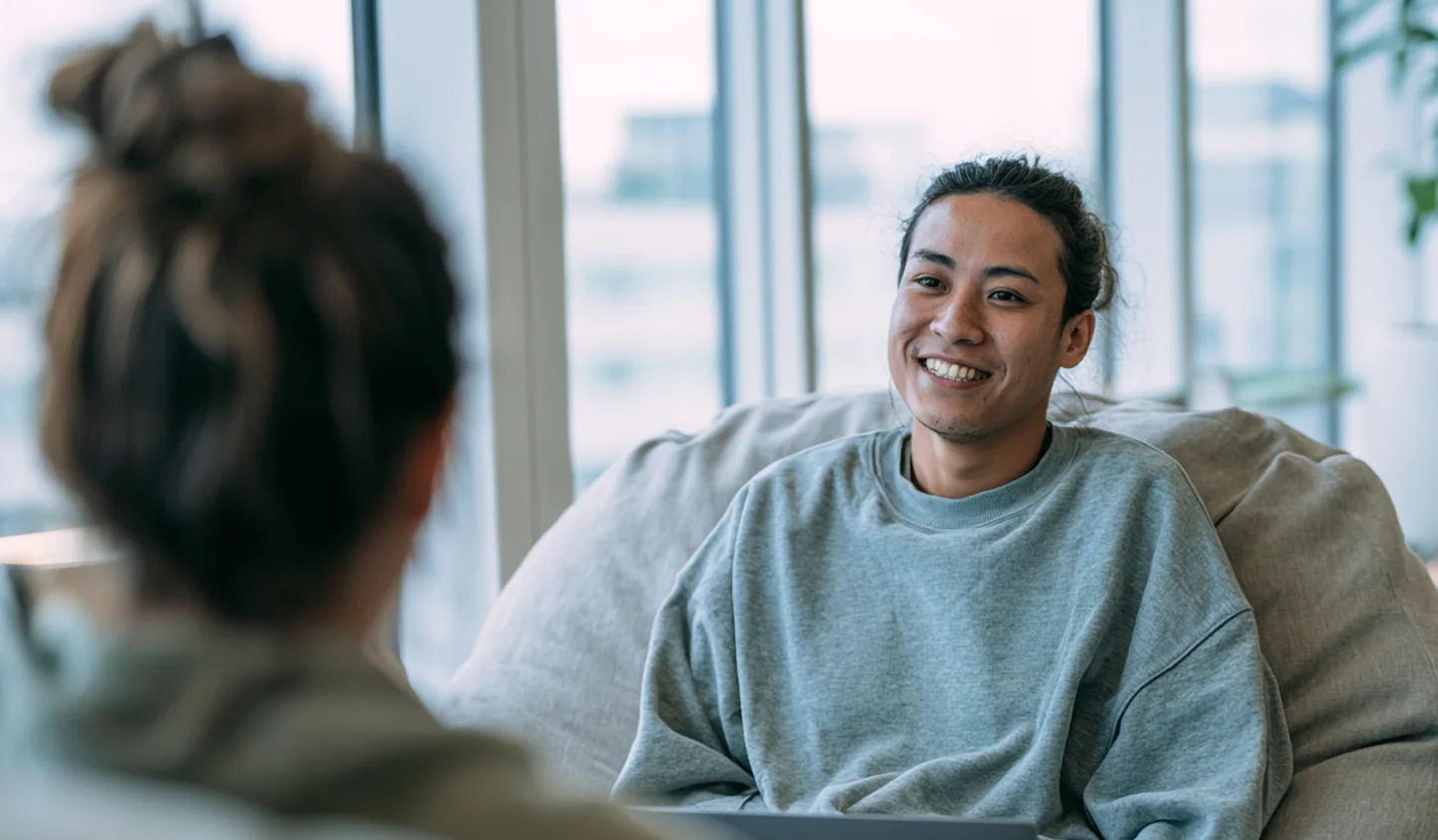 Smiling team member with a laptop talking with a colleague